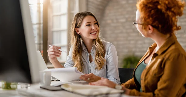 Evenementplanner die bruilofts- of vieringsdetails bespreekt met een klant tijdens een planningsconsultatie in een moderne kantooromgeving.