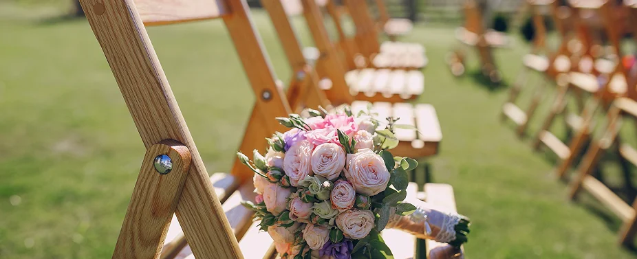 Bruidsboeket geplaatst op houten ceremon stoelen bij een buitenbruiloftlocatie voor de ceremonie.