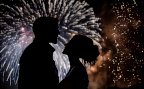 Romantisch silhouet van een bruidspaar dat samen naar vuurwerk kijkt tijdens een avondviering.