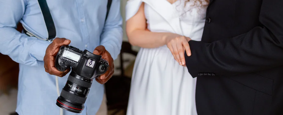 Bruiloftfotograaf die camerainstellingen toont aan een stel tijdens de voorbereidingen voor het evenement voor de ceremonie.