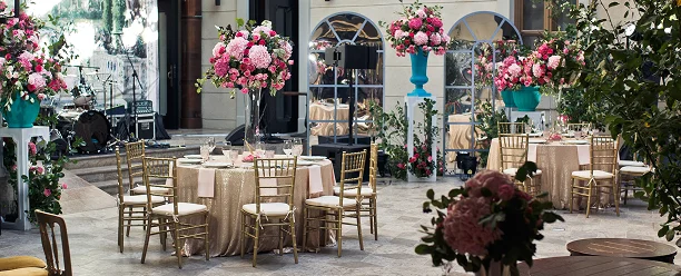 Buiten bruiloft receptiegebied met ronde tafels, elegante stoelen en grote bloemstukken, klaar voor de viering.